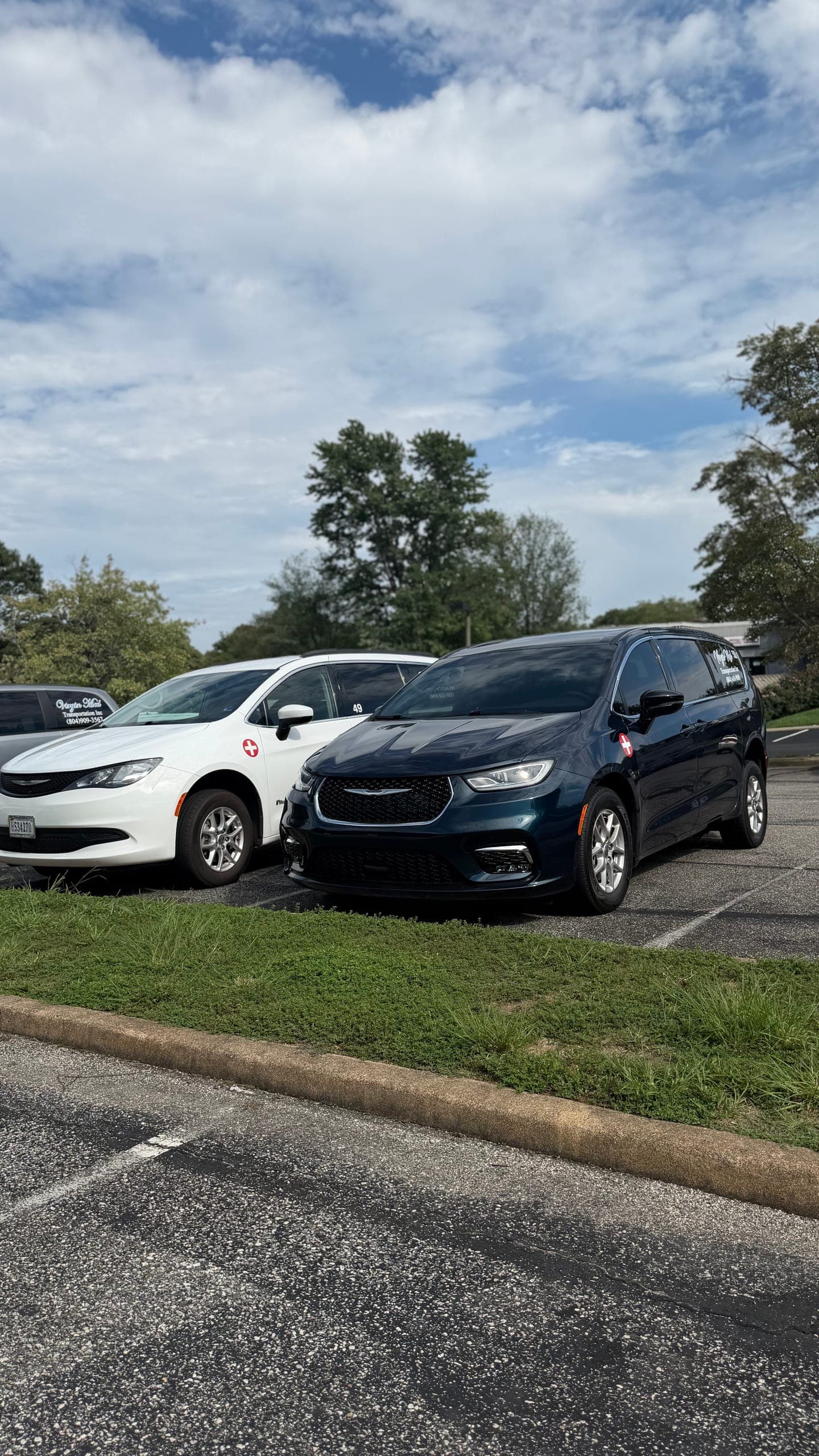A white and a dark blue Virgin Med minivan parked across the lot