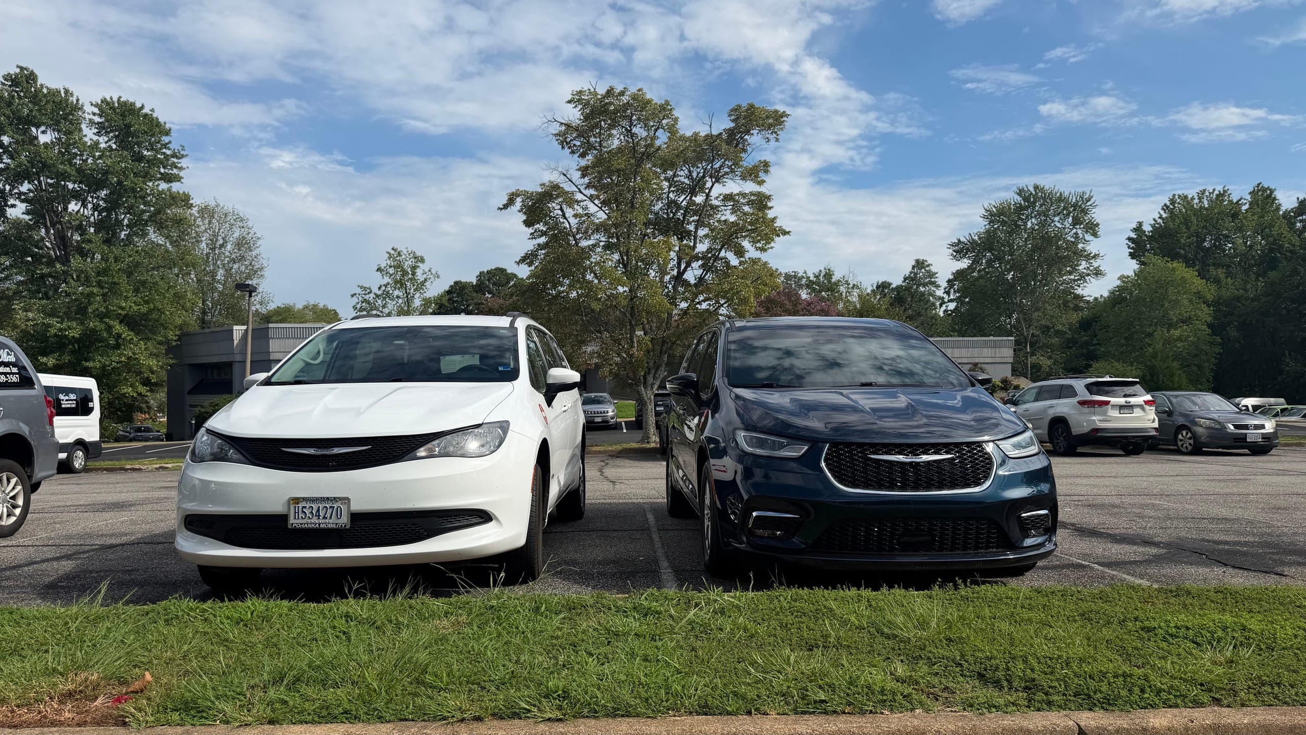 A white and a dark blue Virgin Med minivan side by side