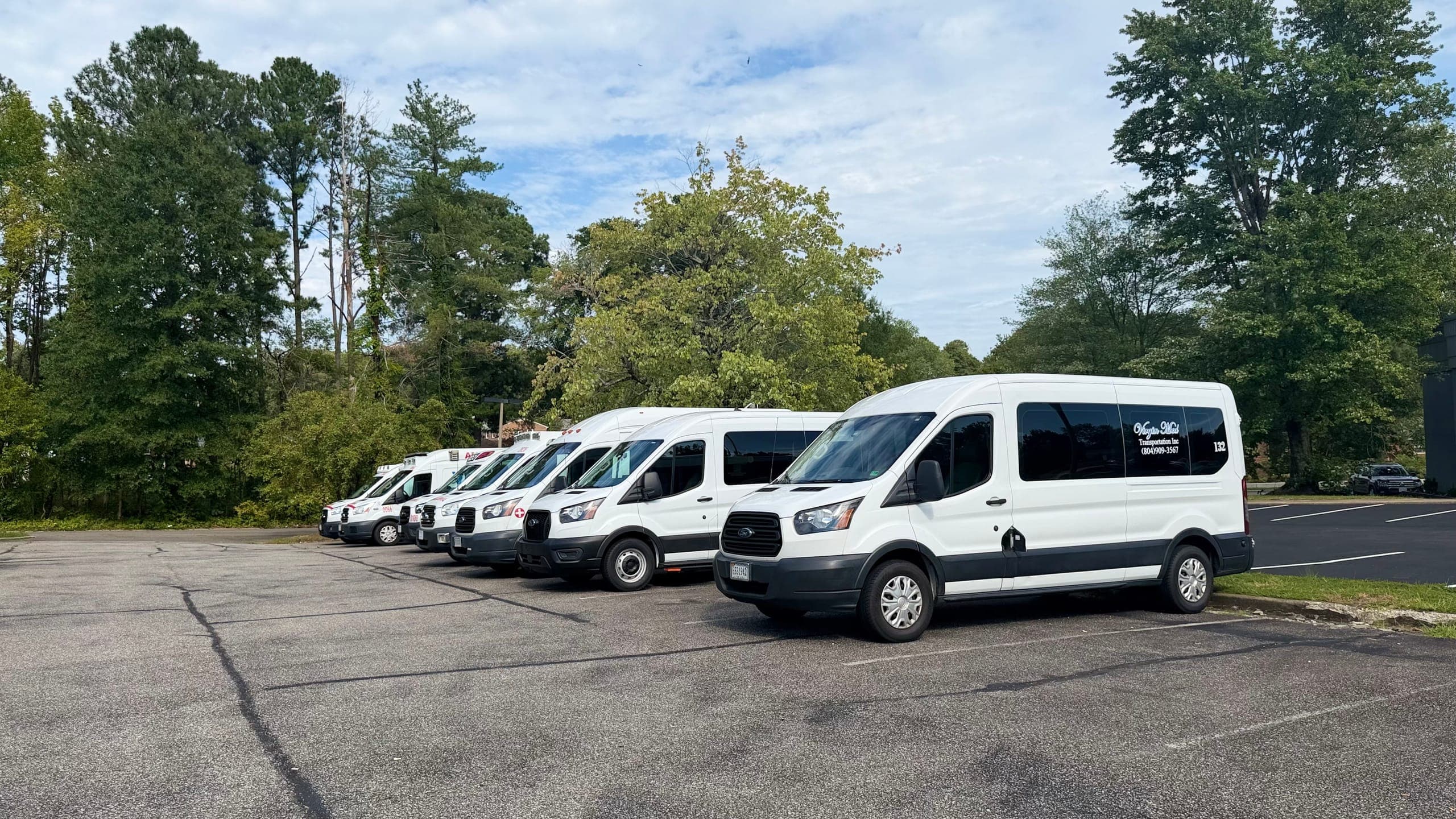 A row of white Virgin Med passenger vans parked in the lot